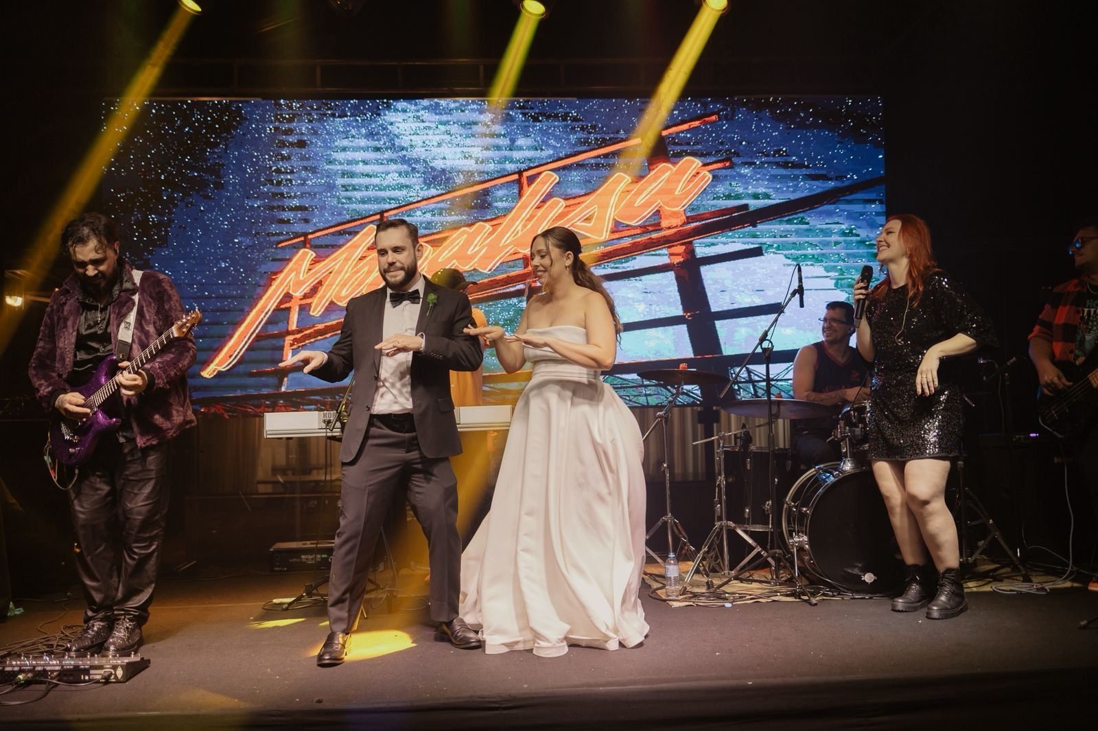 Noivos dançando no palco com o logo da Monalisa no telão